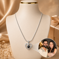Silver necklace with a heart-shaped pendant on a mannequin bust, with a couple photo inset.