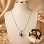 Silver necklace with a heart-shaped pendant on a mannequin bust, with a couple photo inset.